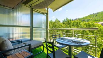 Un balcón con una mesa, sillas, un sofá y vistas a un paisaje verde.