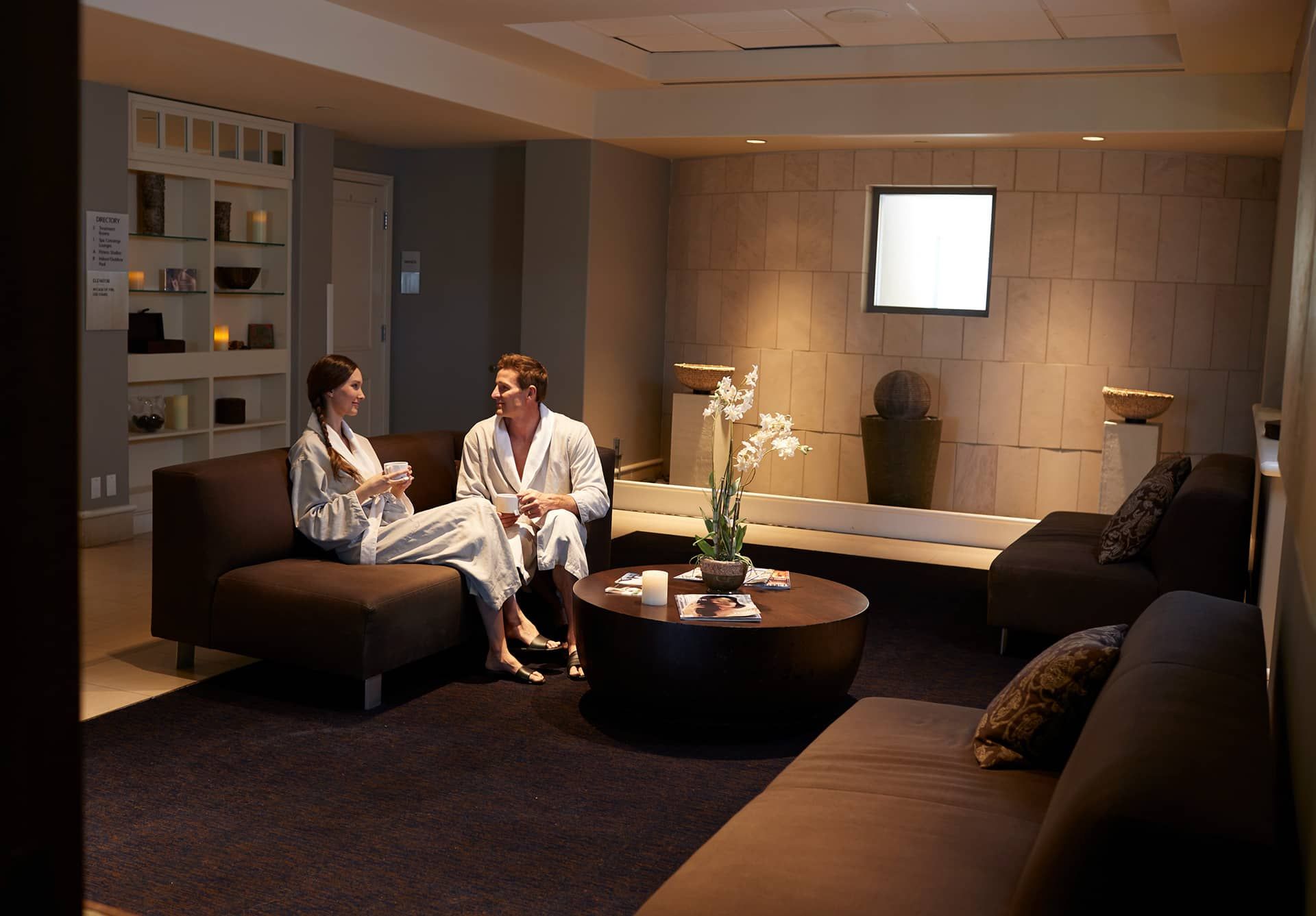 A modern spa room with two sofas, a coffee table, and a reception desk.