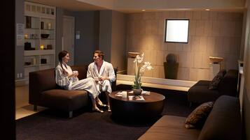 A modern spa room with two sofas, a coffee table, and a reception desk.