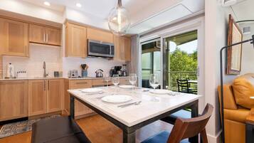 A modern kitchen with wooden cabinets, a central island with seating, and a dining area with a table set for four.