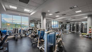 A gym with various exercise equipment, large windows, and a view of the outdoors.