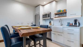 A modern kitchen with white cabinets, a wooden dining table, and blue chairs.