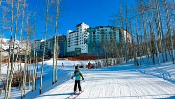 A ski resort with a large building in the background, surrounded by snow-covered trees.