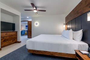 Ein Hotelzimmer mit einem Bett, einem Holzschrank, einem Fernseher und einem Deckenventilator.