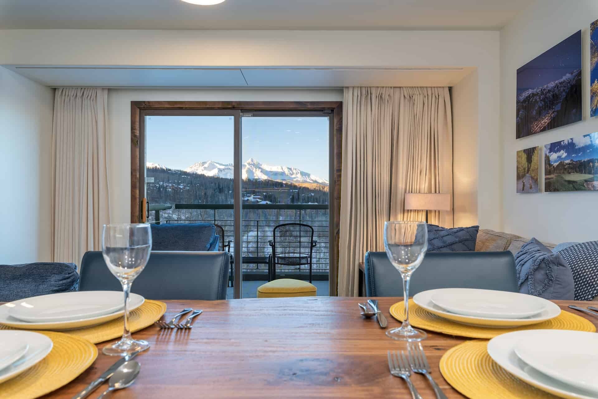 A dining area with a mountain view, a balcony with a chair, and a sofa.