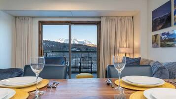A dining area with a mountain view, a balcony with a chair, and a sofa.