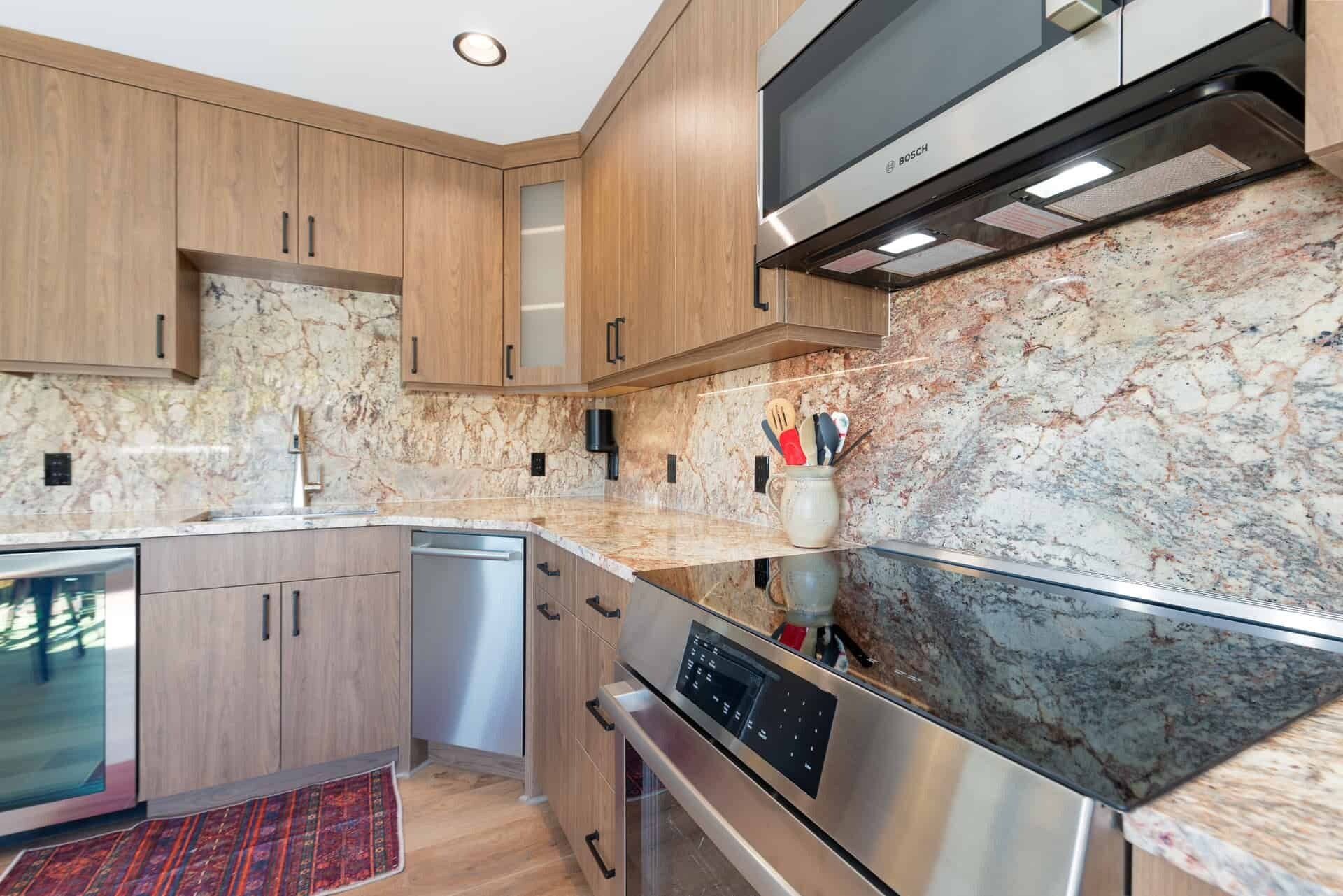 A modern kitchen with wooden cabinets, a stainless steel Bosch oven, and a marble backsplash.