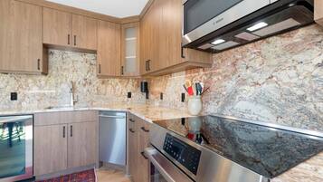 A modern kitchen with wooden cabinets, a stainless steel Bosch oven, and a marble backsplash.