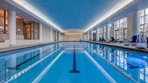 En lång inomhuspool med tydliga markeringar för banorna, stora fönster och en ljus interiör.