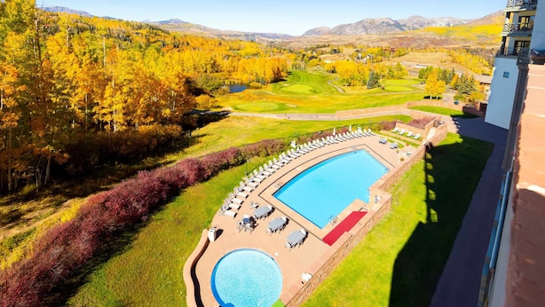 Ett hotell med en swimmingpool, ett sällskapsrum och utsikt över en golfbana och berg.
