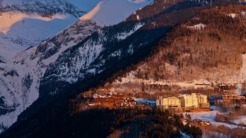 A mountain resort with a large lodge and cabins, surrounded by snow-covered peaks and forested slopes.