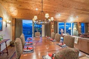 Uma sala de jantar com teto de madeira, janelas amplas e um lustre.