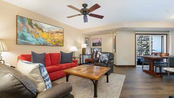 A living room with a red sofa, a brown leather couch, a wooden coffee table, and a ceiling fan.