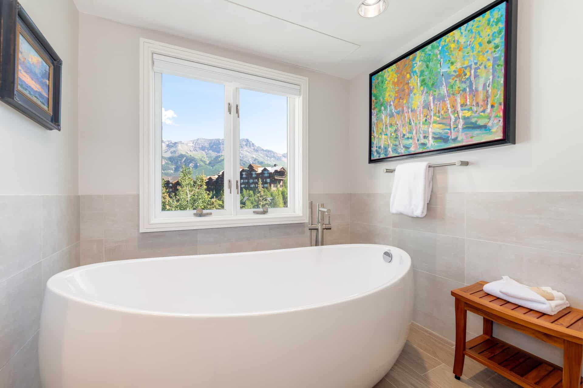 Un baño con una bañera independiente, una ventana con vistas a la montaña y un cuadro en la pared.