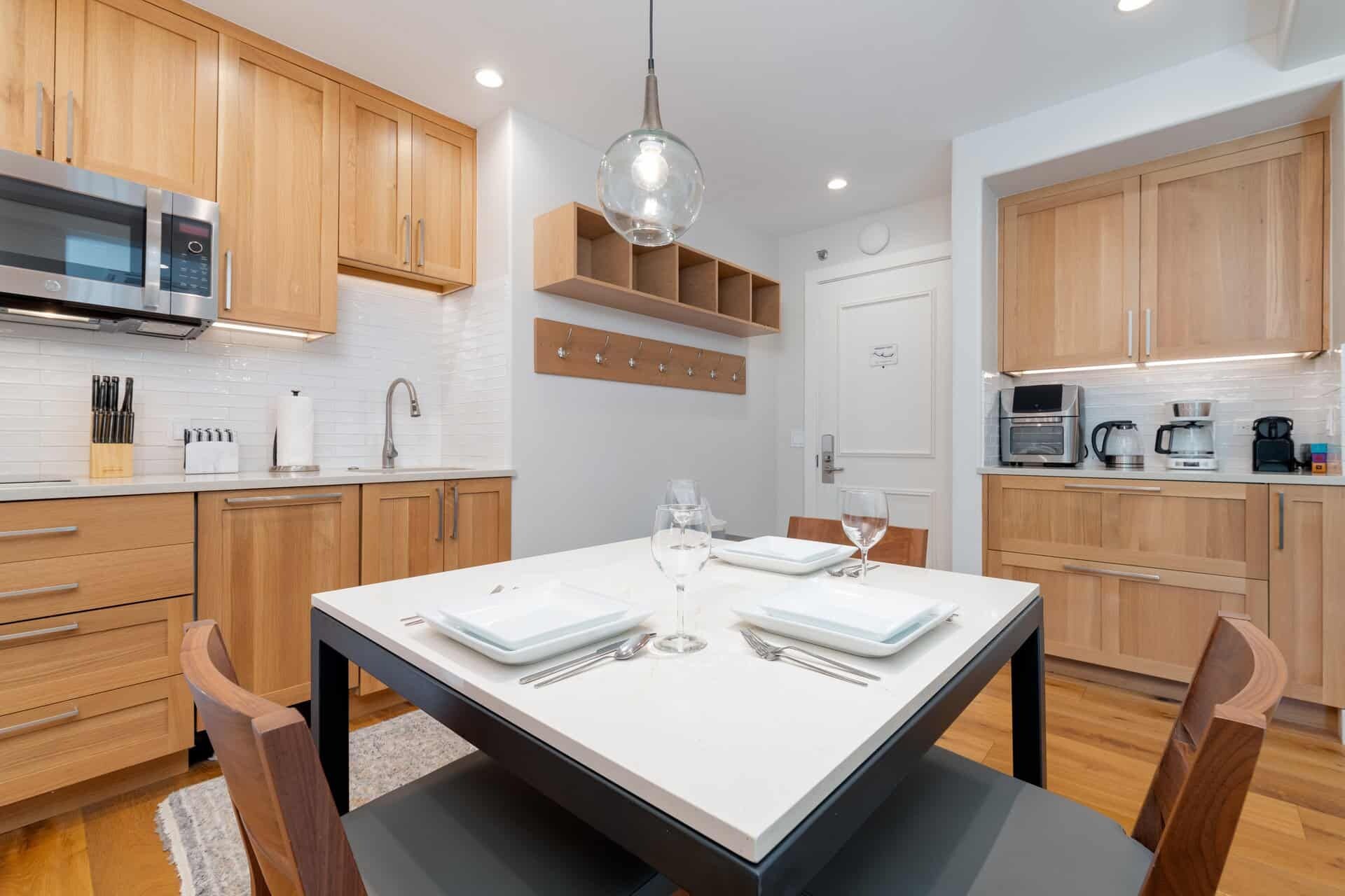 A modern kitchen with wooden cabinets, a built-in microwave, and a dining area with a table set for two.