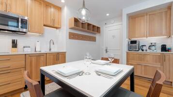 A modern kitchen with wooden cabinets, a built-in microwave, and a dining area with a table set for two.