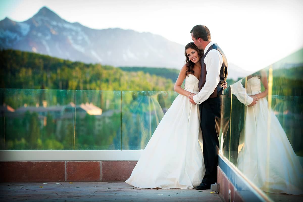 A couple embracing on a balcony with a mountain view.