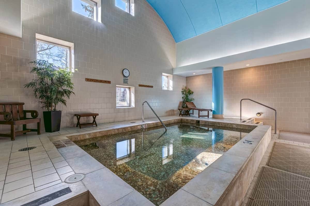 A swimming pool with a tiled floor, a clock on the wall, and a blue ceiling.