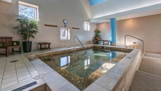 En swimmingpool med ett kaklat golv, en klocka på väggen och ett blått tak.