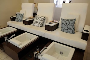 Ein Hotelbad mit mehreren Waschbecken, einer Couch mit gemusterten Kissen und einem Mülleimer.