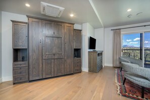 A spacious room with a large wardrobe, a flat-screen TV, and a balcony with a view. - Ski-In/Ski-Out 1BR Suite | Mtn. & Pool Views + Spa (Mountain Village)