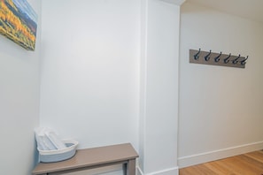A hallway with a coat rack, a basket on a bench, and a painting on the wall. - Ski-In/Ski-Out 1BR Suite w/ Balcony Views + Pools (Mountain Village)
