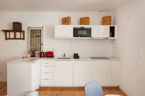 A compact kitchen with white cabinetry, a microwave, a toaster, and a coffee maker. - Alfama Duplex with River Views (Lisbon)