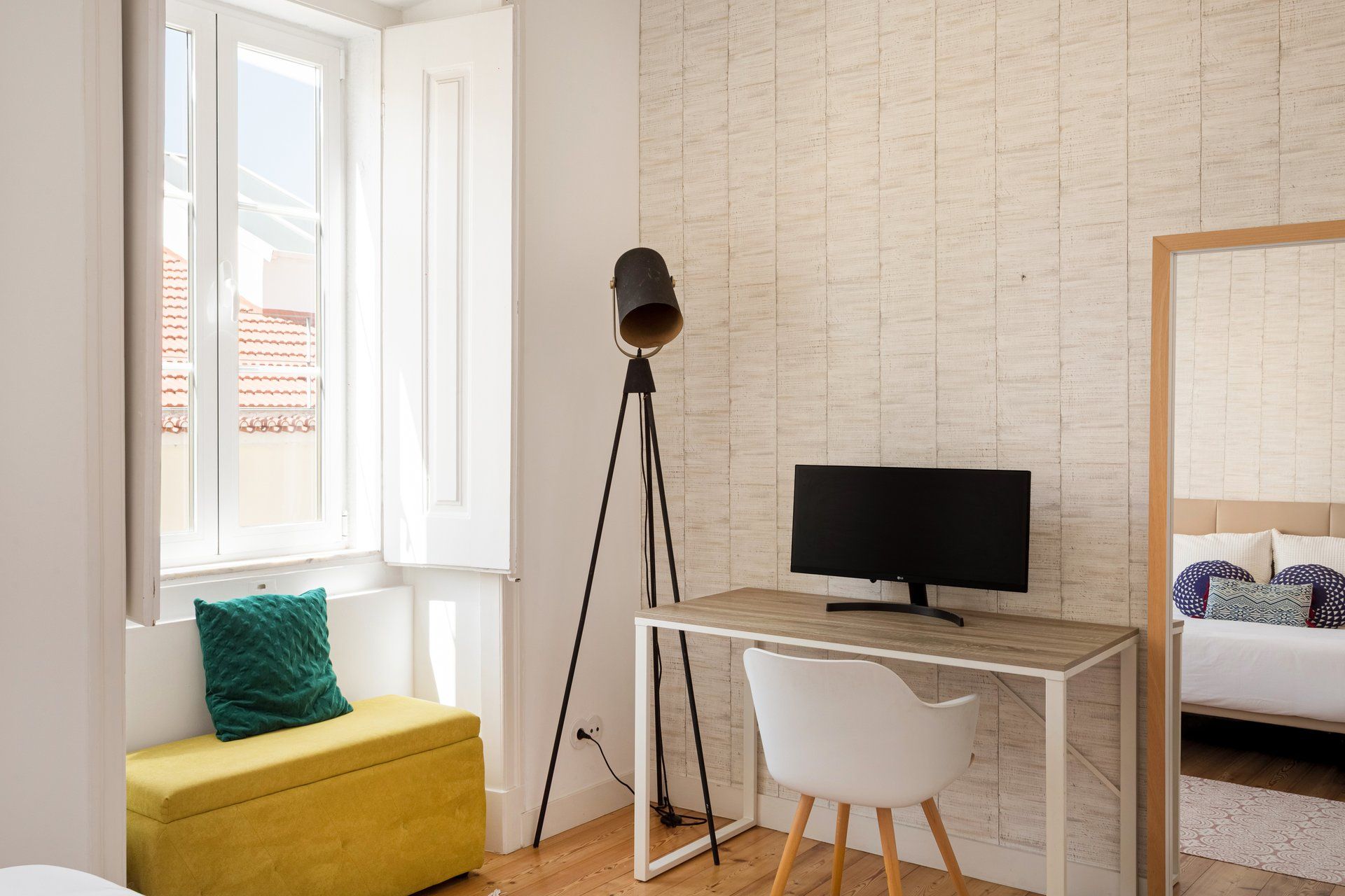 A room with a desk, a chair, a television, a lamp, and a bed.