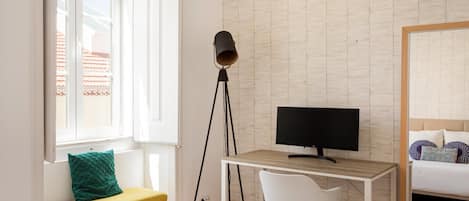 Une pièce comprenant un bureau, une chaise, un téléviseur, une lampe et un lit.