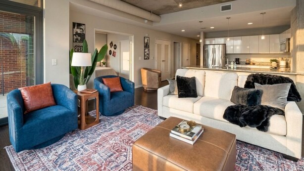 A modern living room with a blue sofa, a white sofa, and a coffee table. There is a kitchen in the background. - Spacious 3-bedroom apartment with AC in soothing Cleveland (Cleveland)