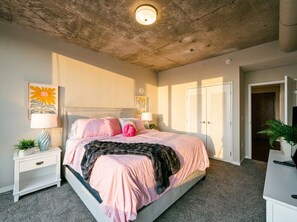 Ein Schlafzimmer mit Bett, Nachttischen, einer Deckenleuchte und einer Tür.