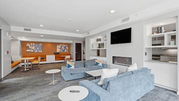 A modern living room with a sofa set, a coffee table, and a TV mounted on the wall.