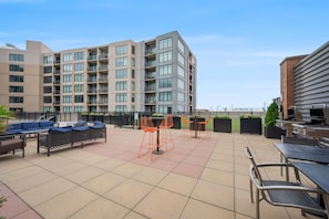 A rooftop patio with outdoor seating, a barbecue area, and a view of a multi-story building. - Spacious 3-bedroom apartment with AC in soothing Cleveland (Cleveland)
