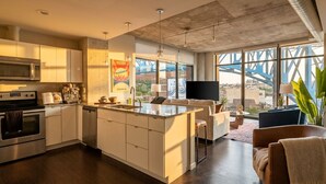 A modern kitchen with a central island, built-in appliances, and large windows offering a view of a bridge. - Spacious 3-bedroom apartment with AC in soothing Cleveland (Cleveland)
