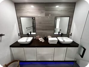 A bathroom with two sinks, a large mirror, and a dark countertop. - Modern 1-bedroom private studio with AC (Las Vegas)