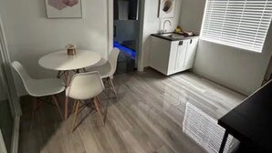 Cocina compacta con comedor, ventilador de techo y ventana con persianas.