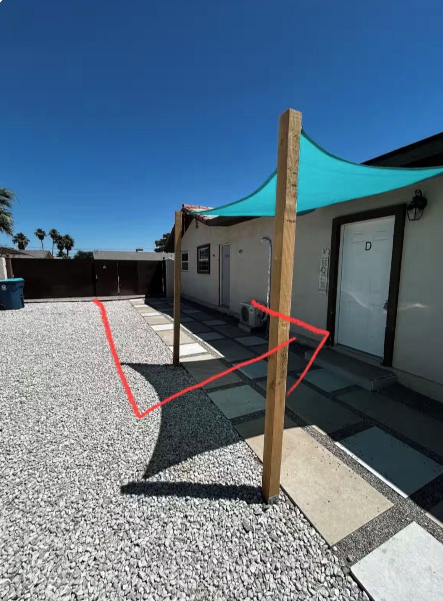 A building with a covered outdoor area, a gravel ground, and a wooden post.