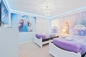 A bedroom with two beds, a ceiling fan, and wall art. - Luxury 7BR Disney Home • Pool Spa • Game Room -  Resort Windsor Island (Four Corners)