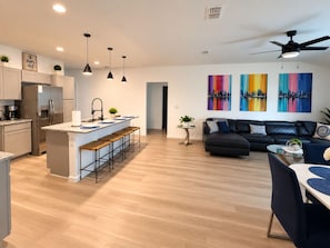 Una cocina moderna con una isla central, taburetes de bar y un refrigerador.