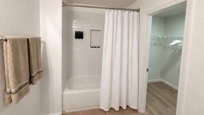 A bathroom with a bathtub, a shower curtain, and a towel rack with towels. - New 5BR Home . Walk to Dining . Sleeps 10 (Jacksonville)