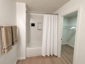 Un baño con bañera, cortina de ducha y toallero con toallas.