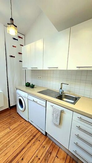 A compact kitchen with white cabinets, a washing machine, and a sink. - Skylight Mouraria Loft (Lisbon)