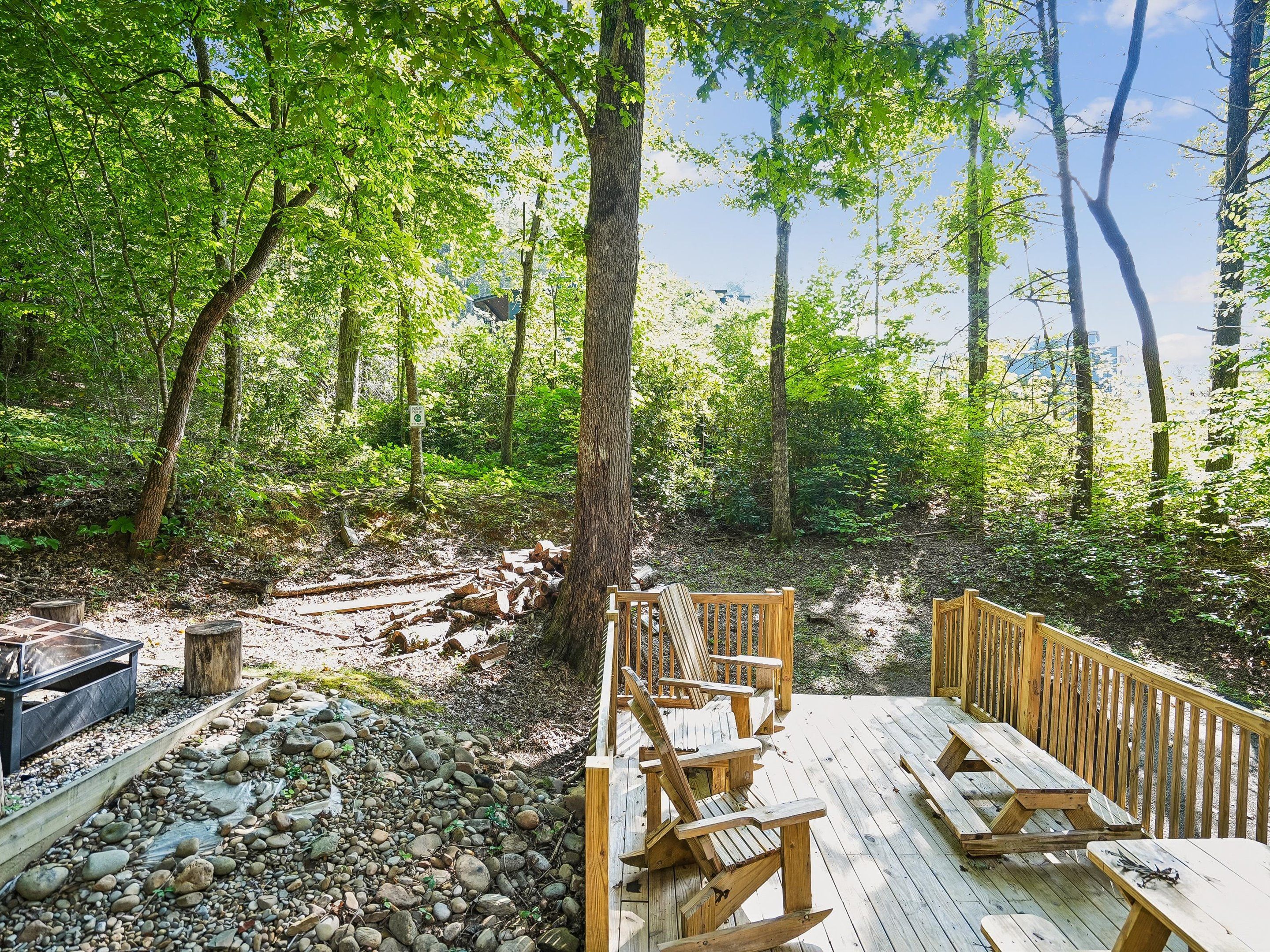 A wooden deck with picnic tables and a grill in a forested area.