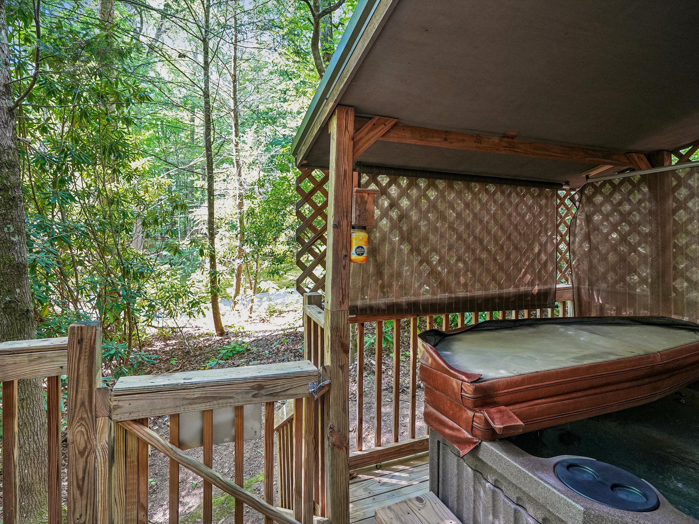 A hot tub with a wooden deck and a wooden fence, surrounded by trees.