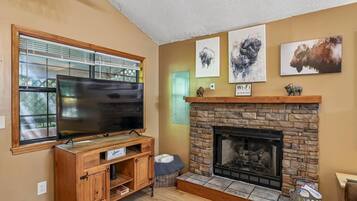 A living room with a fireplace, a television, and artwork on the wall.