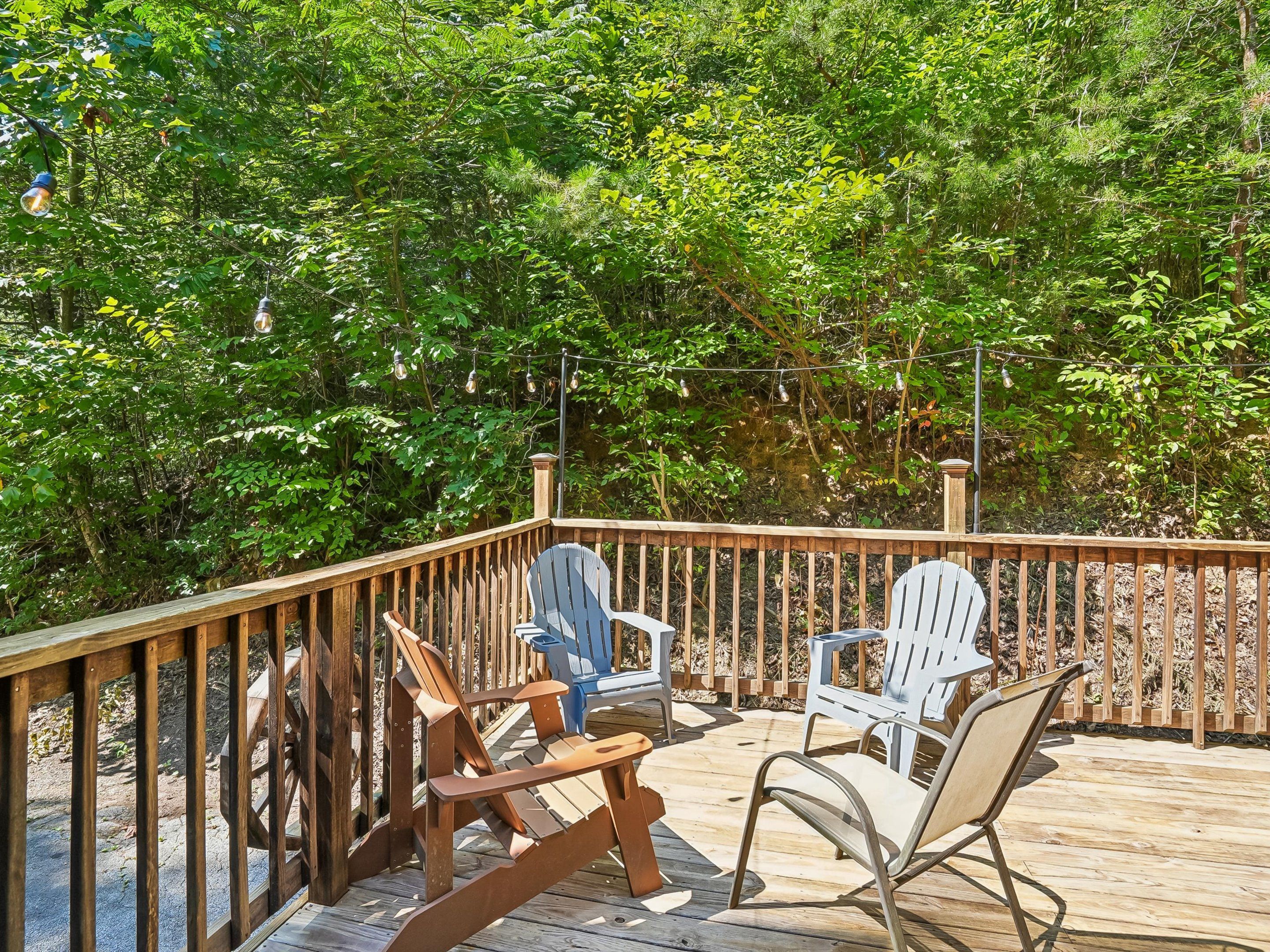 Een houten terras met Adirondack-stoelen en een lichtslingering.