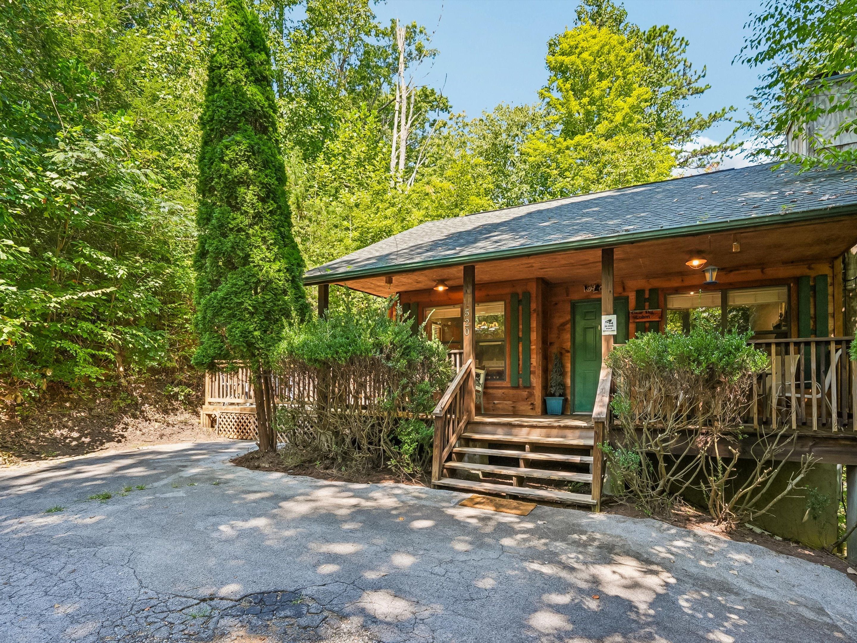 A cabin with a porch, steps leading up to the entrance, and a view of the surrounding forest.