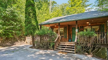 A cabin with a porch, steps leading up to the entrance, and a view of the surrounding forest.