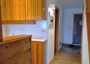 A narrow hallway with wooden flooring, a white wall, and a door at the end. - Desirable 1-bedroom & Loft condo in Wilson perfect for your getaway (Wilson)