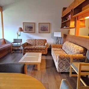 A cozy living room with a sofa, armchair, and a coffee table. There are two framed pictures on the wall and a lamp on the side. - Desirable 1-bedroom & Loft condo in Wilson perfect for your getaway (Wilson)